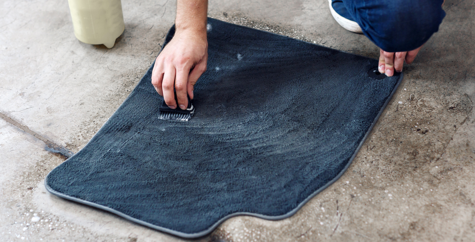 Person cleaning a car floor mat