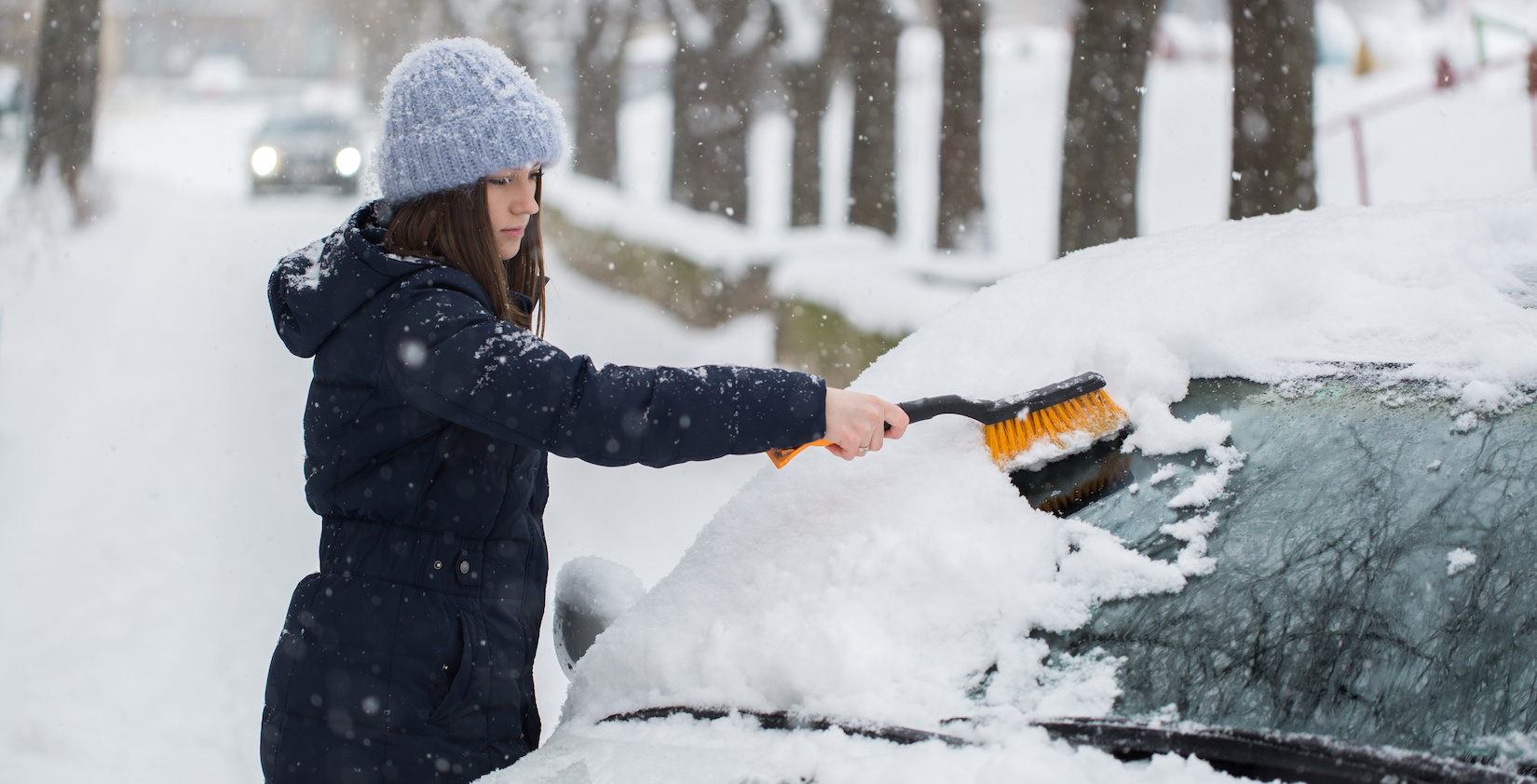 A person removing snow from her car
