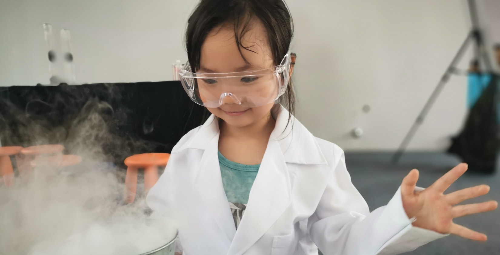 Little kid doing science experience with protection glasses on.