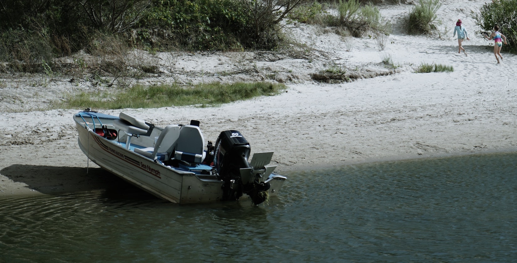 Little boat docked on a beach with two people in background