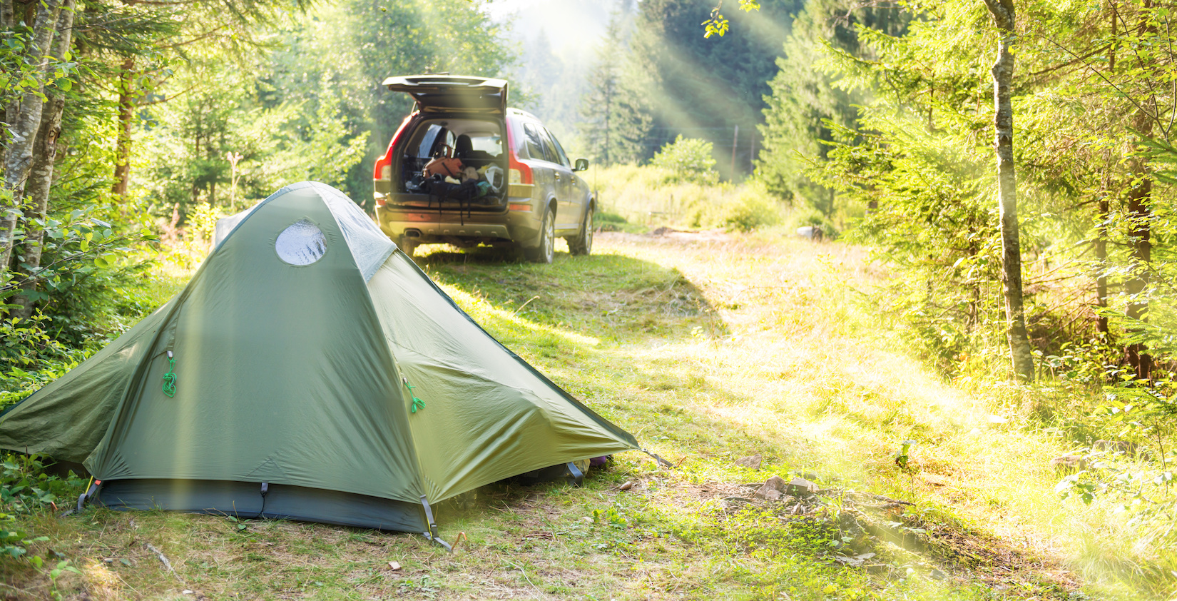 Set up tent in front of a car with its trunk open