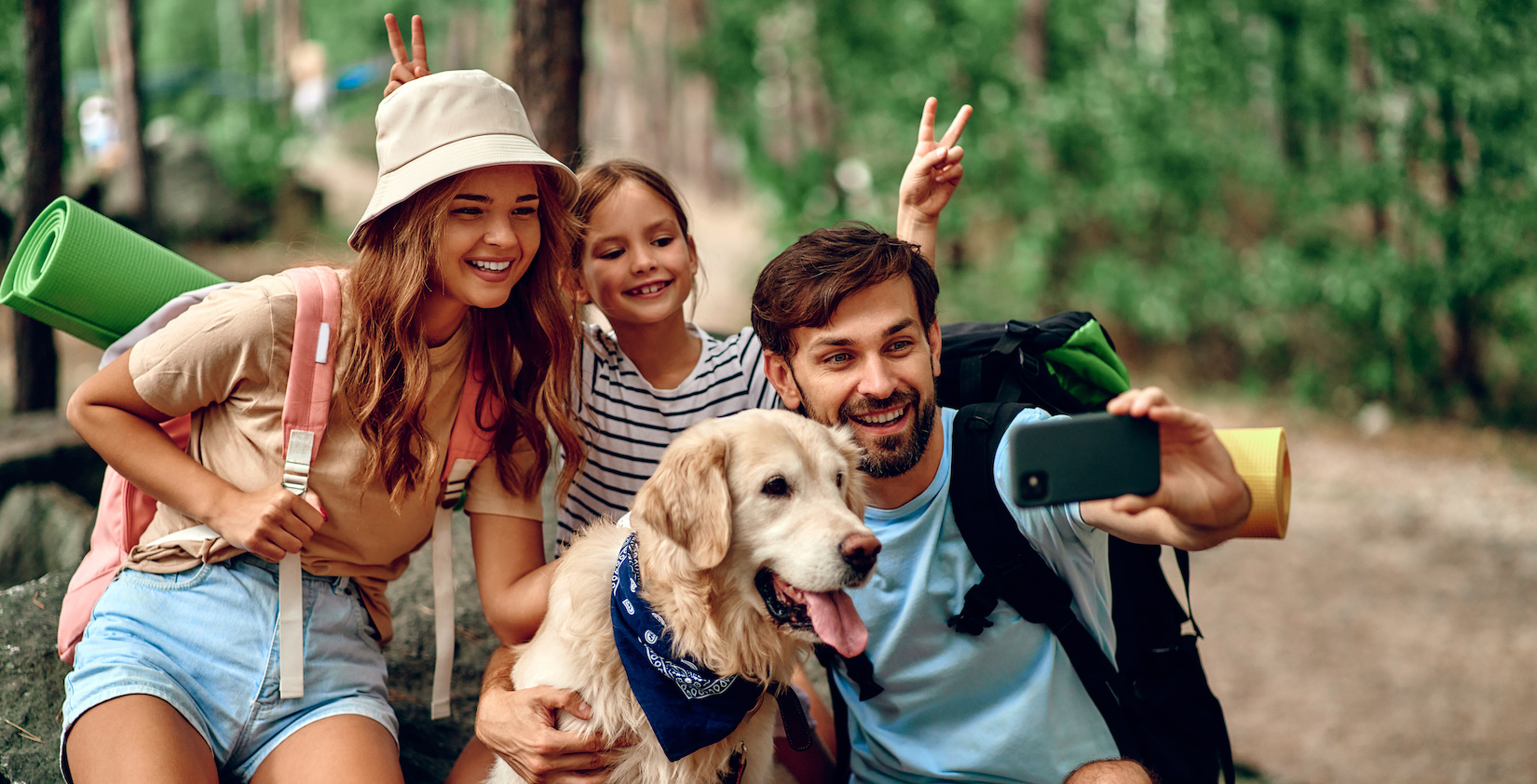 Three people and a dog taking a selfie in the forest